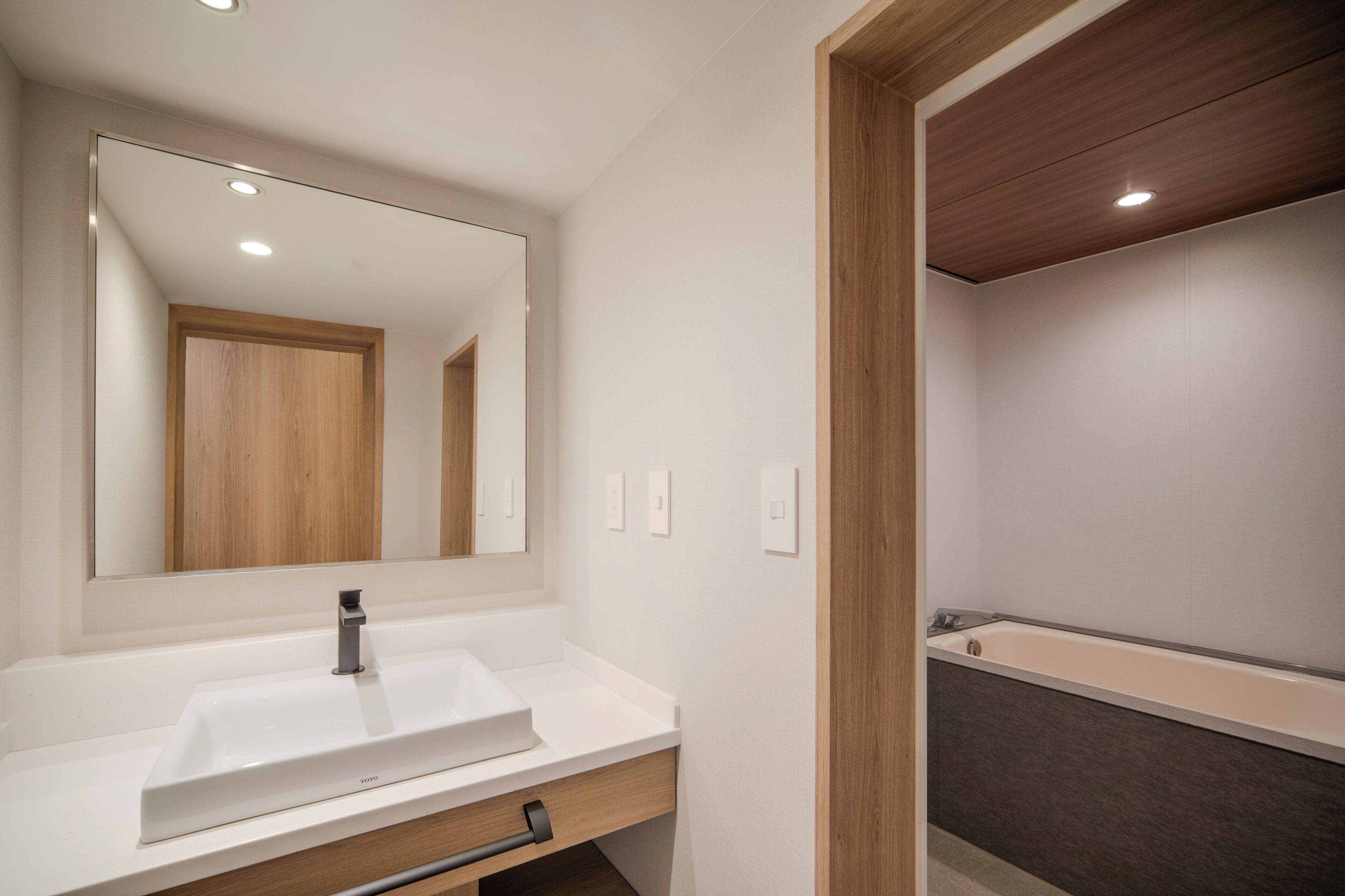 A bathroom with a white sink, mirror, and wooden vanity.