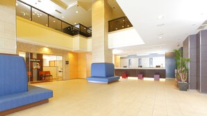 Un hall d’entrée spacieux comprenant un café pour les voyageurs, des espaces de détente et un comptoir d’accueil.