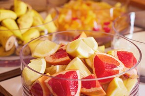 A clear glass bowl filled with sliced fruits, including citrus and possibly grapefruit, with a blurred background of more fruits. - Hotel MyStays Nagoya - Sakae (Nagoya)