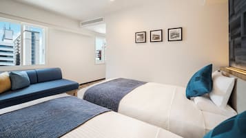 A hotel room with two beds, a sofa, and a large window.