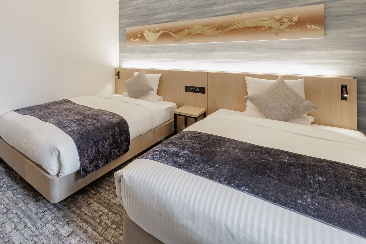 Habitación de hotel con dos camas, una mesita de noche y una obra de arte colgada en la pared.