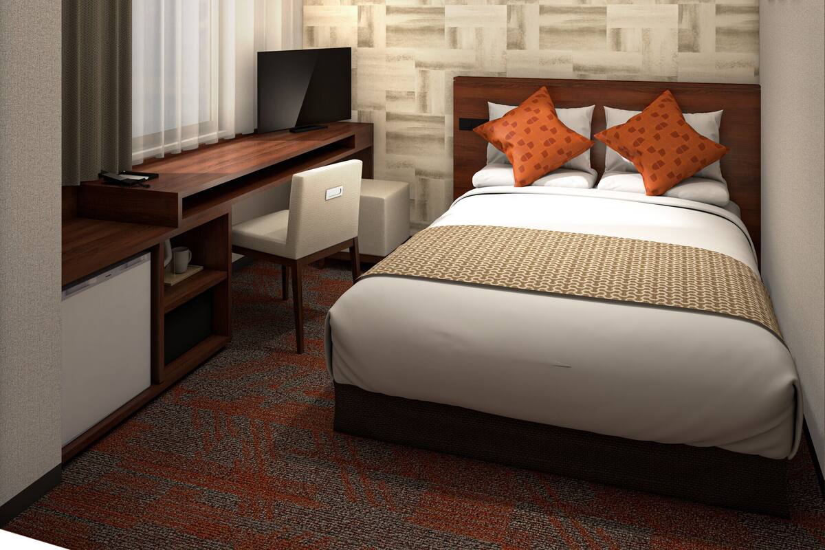Habitación de hotel con cama, escritorio, silla, televisor y pared con diseño.