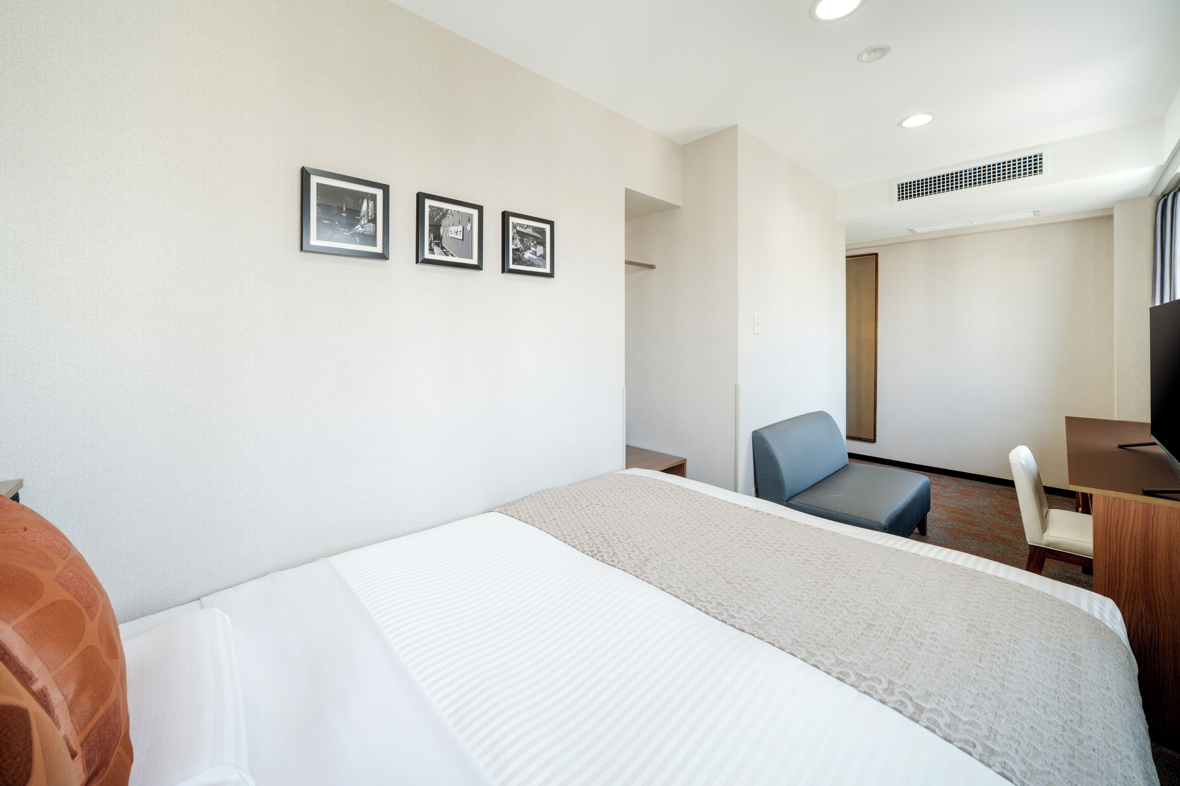 Ein Hotelzimmer mit einem Bett, einem Schreibtisch, einem Sessel und einem Fernseher.