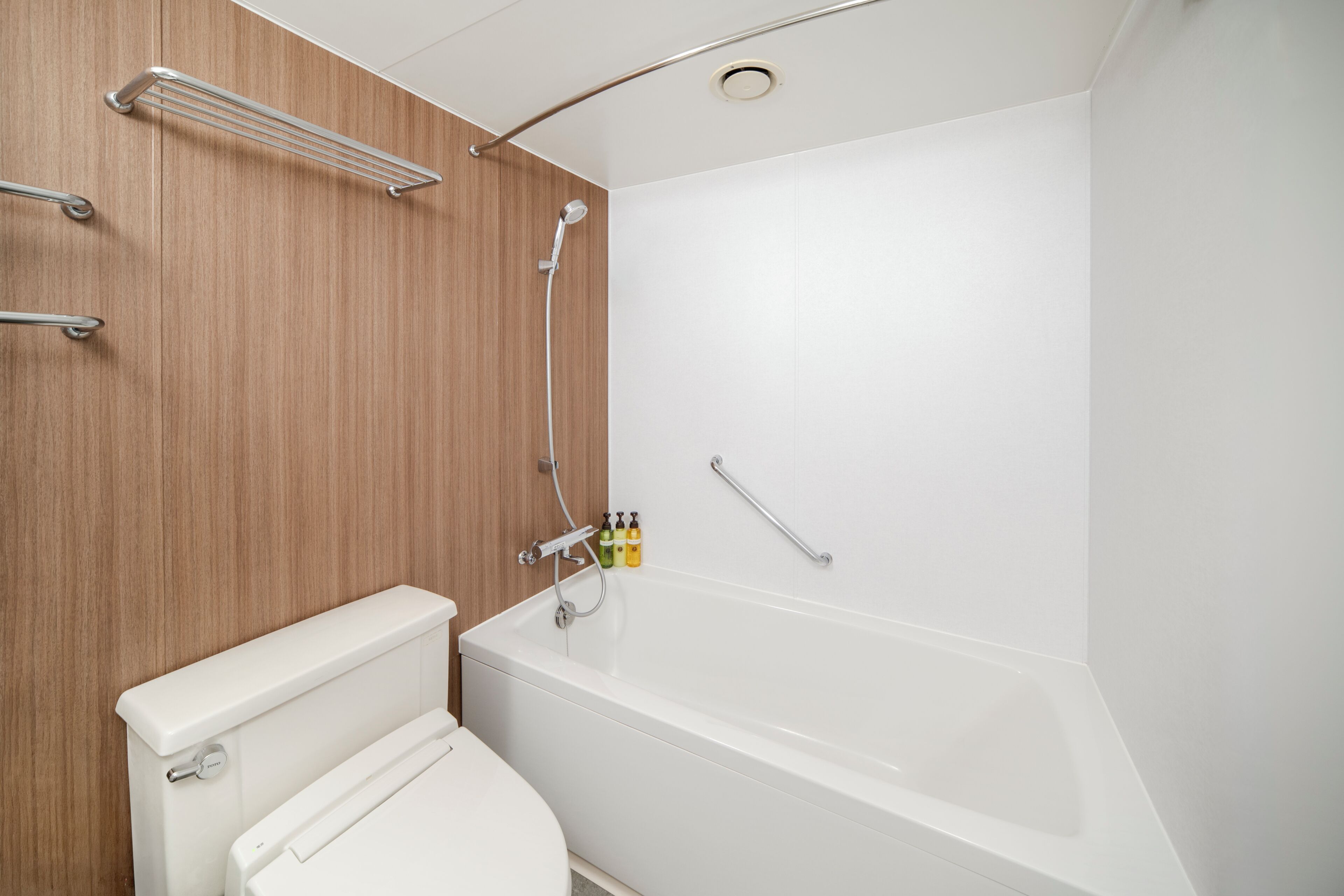 Een moderne badkamer met een wit bad, een toilet en een houten wastafelmeubel.