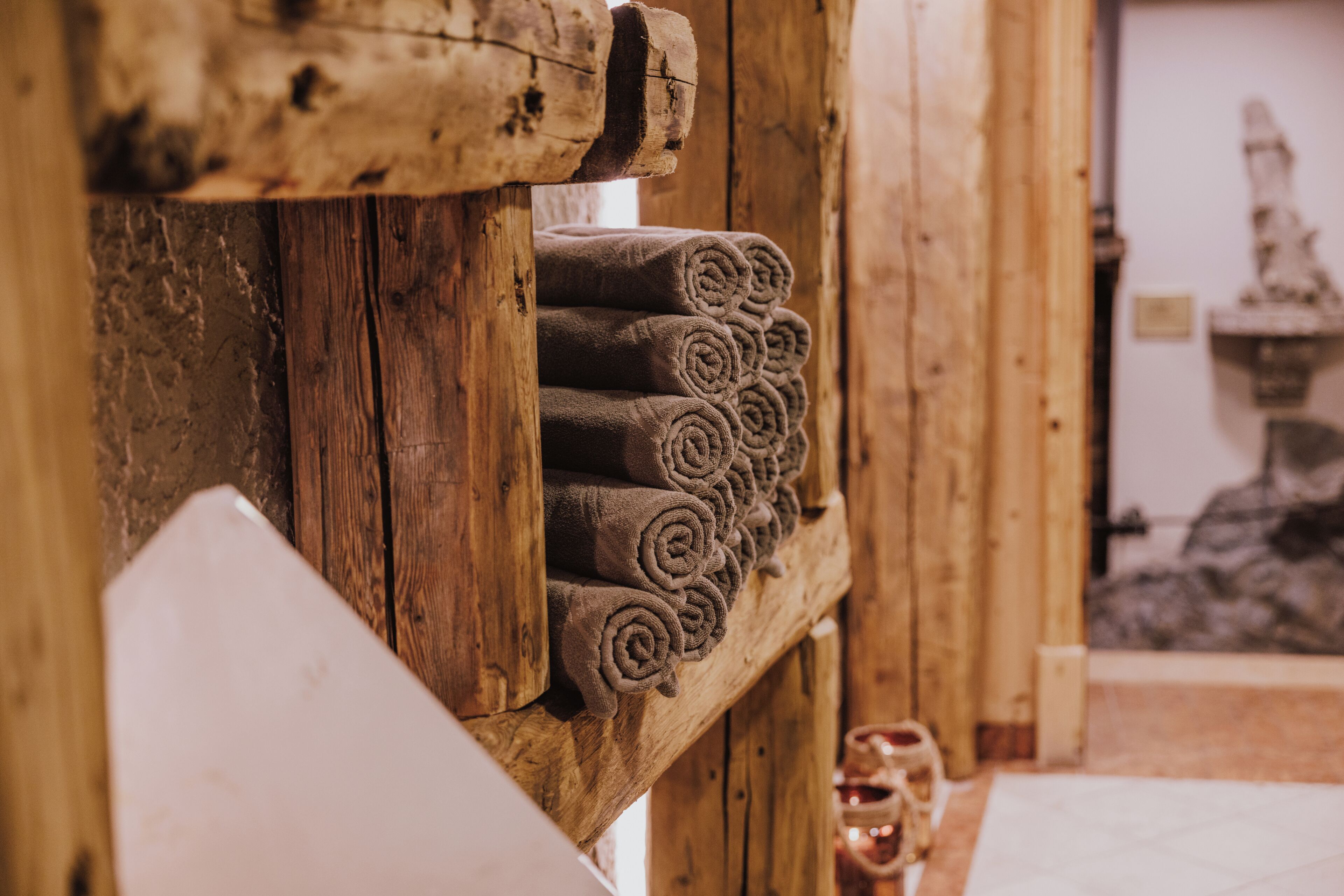 A wooden wall with rolled towels and a statue in the background.