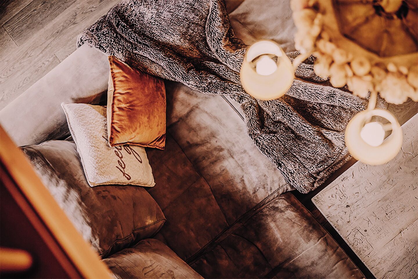 A cozy living room with a plush sofa, a patterned throw blanket, and a decorative lamp.