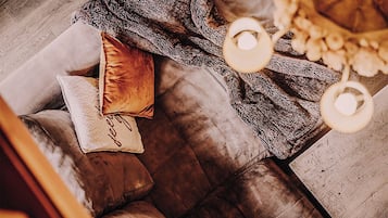 A cozy living room with a plush sofa, a patterned throw blanket, and a decorative lamp.