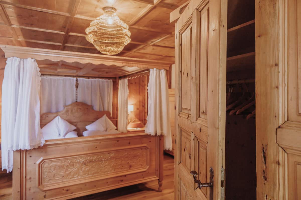 Un dormitorio de madera con cama, cortinas y una araña.