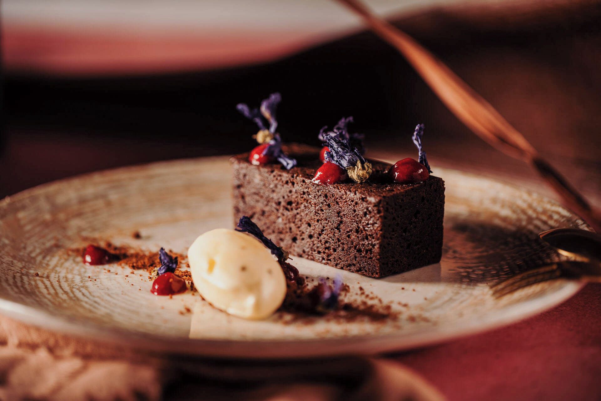 A slice of chocolate cake with berries and a scoop of vanilla ice cream on a plate.