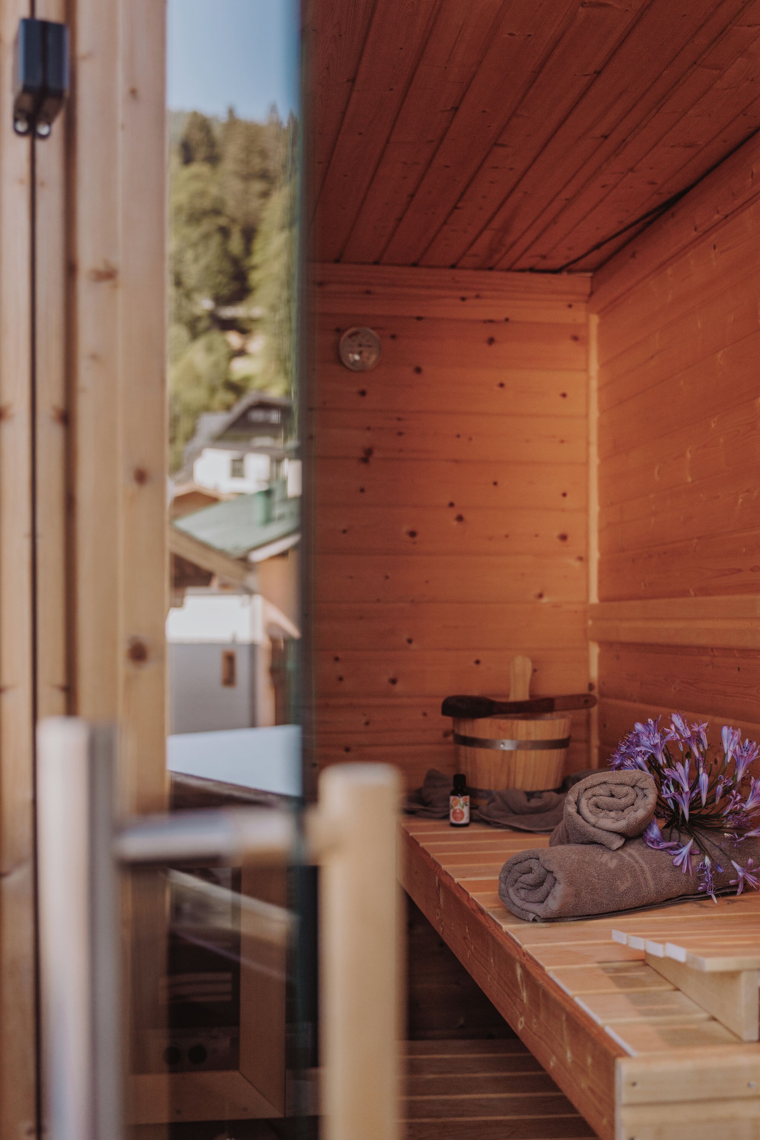 Un sauna en bois, avec un banc, des serviettes et une bouteille d’huile.