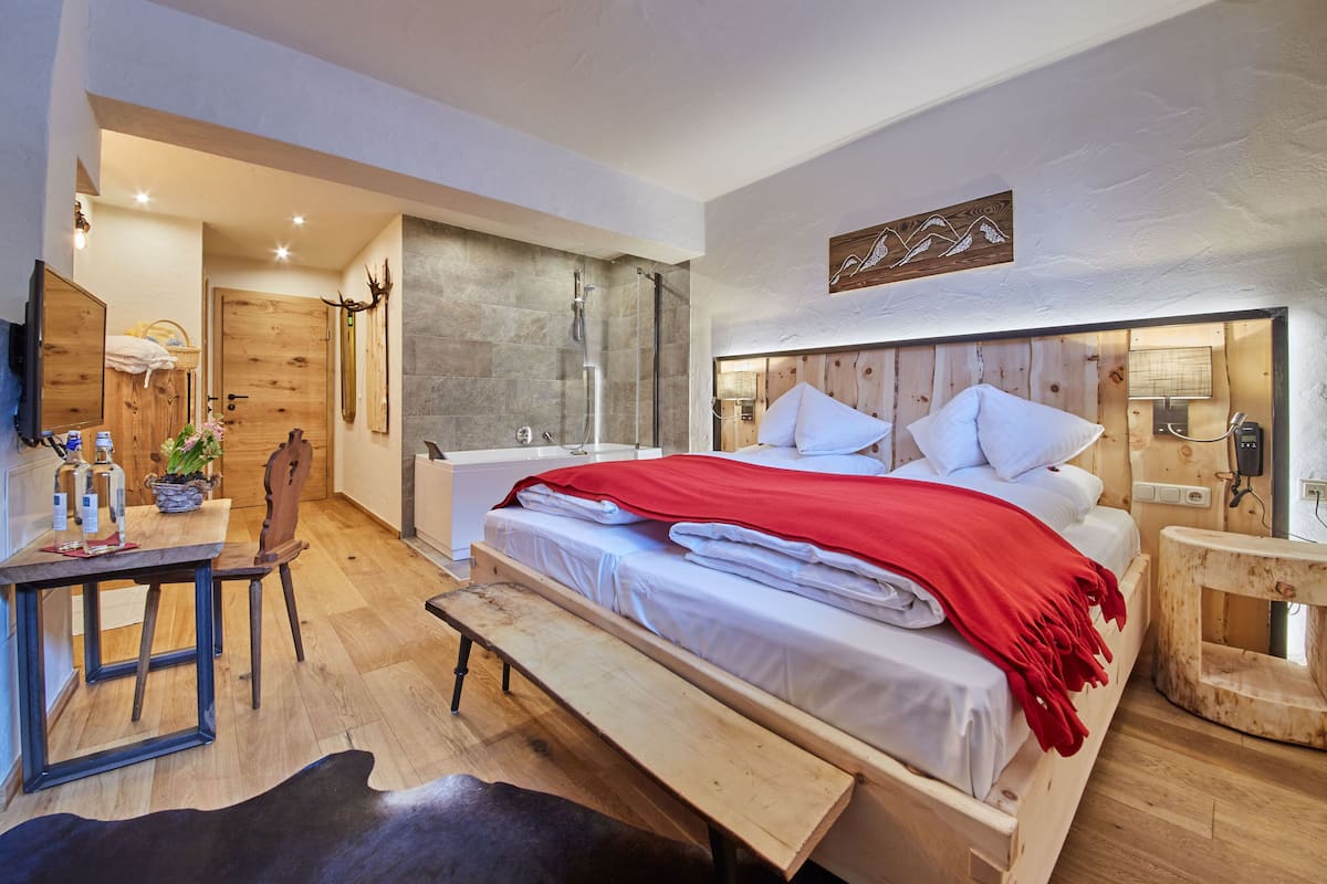 Un dormitorio moderno con una cama de madera, un banco, un escritorio y una zona de ducha.