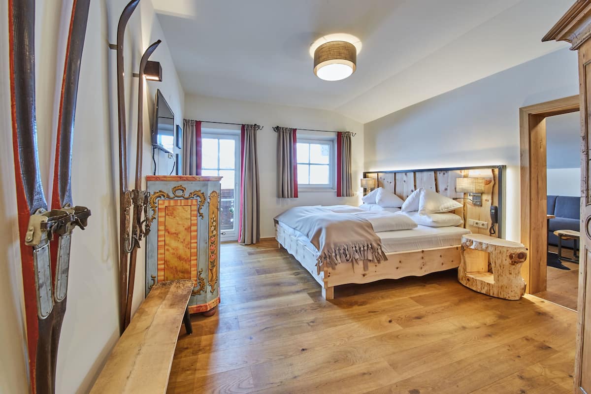 Un dormitorio con cama de madera, una mesita de noche, un espejo y una ventana con cortinas.