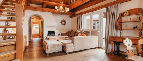 A spacious living area with a wooden staircase, a white sofa, and a wooden desk.
