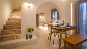 A modern interior with a staircase, dining area, and a cozy seating space. - Margarenia (Santorini)