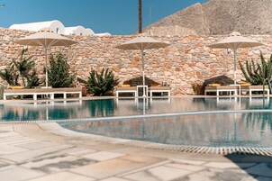 Una piscina al aire libre, sombrillas, sillones reclinables de piscina