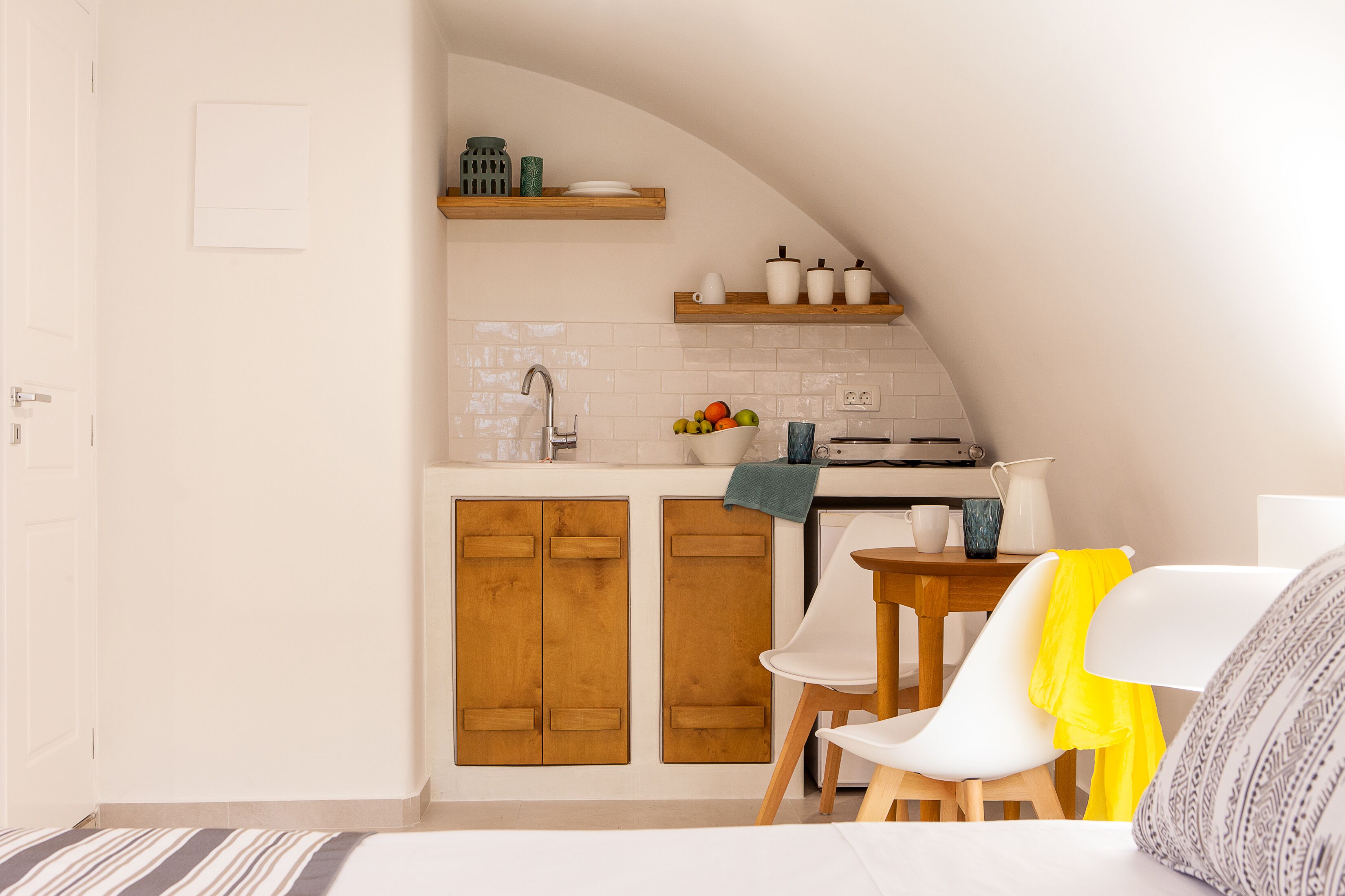 Una cucina compatta con mobili in legno, un lavello e un piccolo angolo ristoro con tavolo e sedie.
