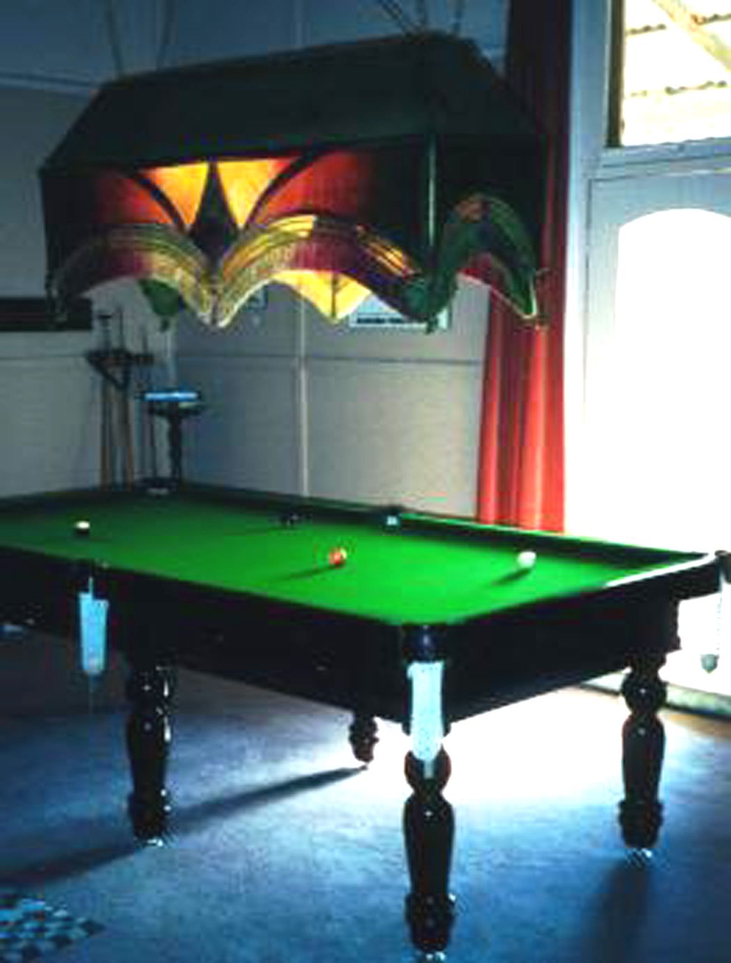 A pool table with a green felt surface, surrounded by a dark-colored table base.