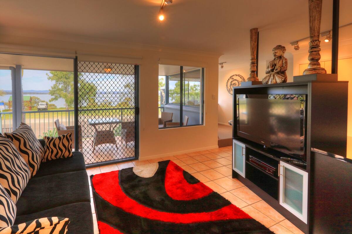 A living room with a sofa, TV, and a view of the outdoors.