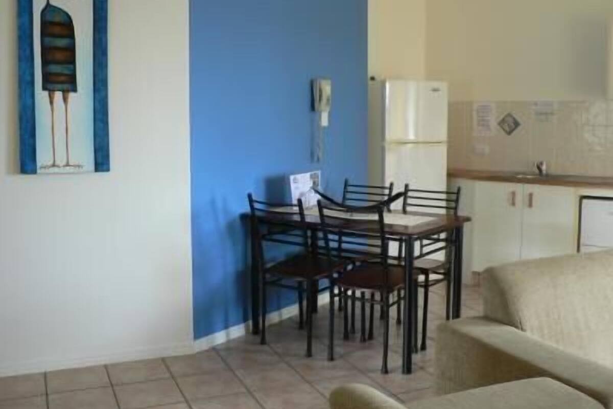 A dining area with a table and chairs, a refrigerator, and a wall-mounted phone.