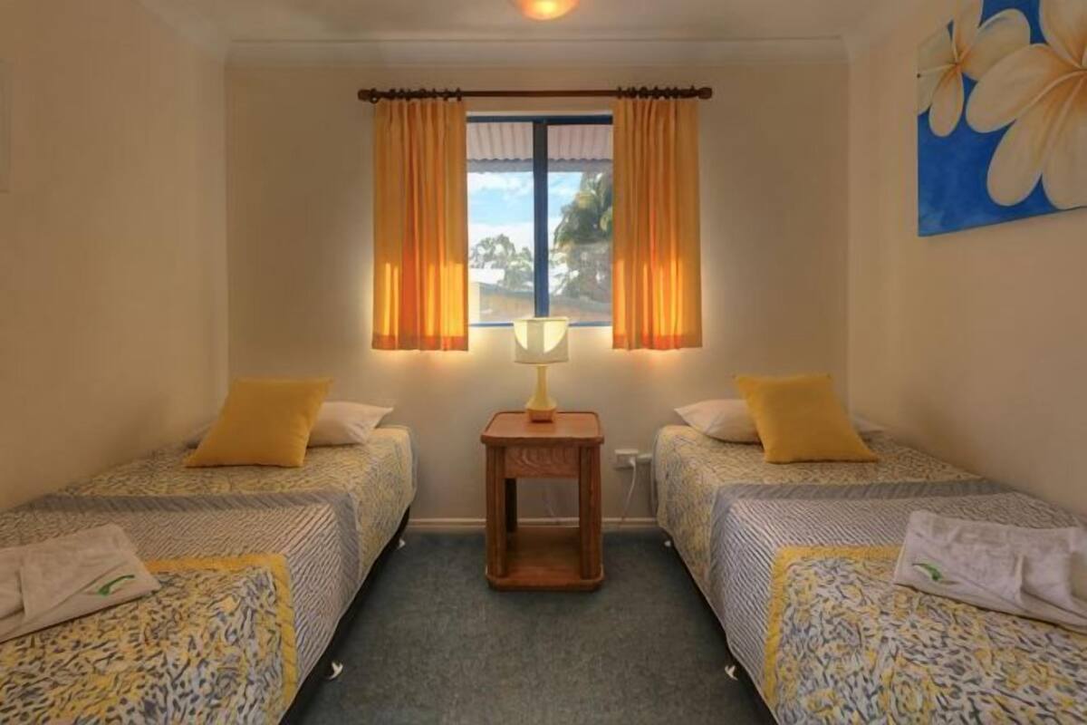 A room with two beds, a small table, and a window with curtains.
