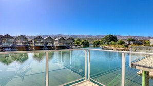 A clear view of a swimming pool with a glass barrier, wooden deck, and a backdrop of mountain ranges. - Lake Resort by Marsden (Mount Pisa)