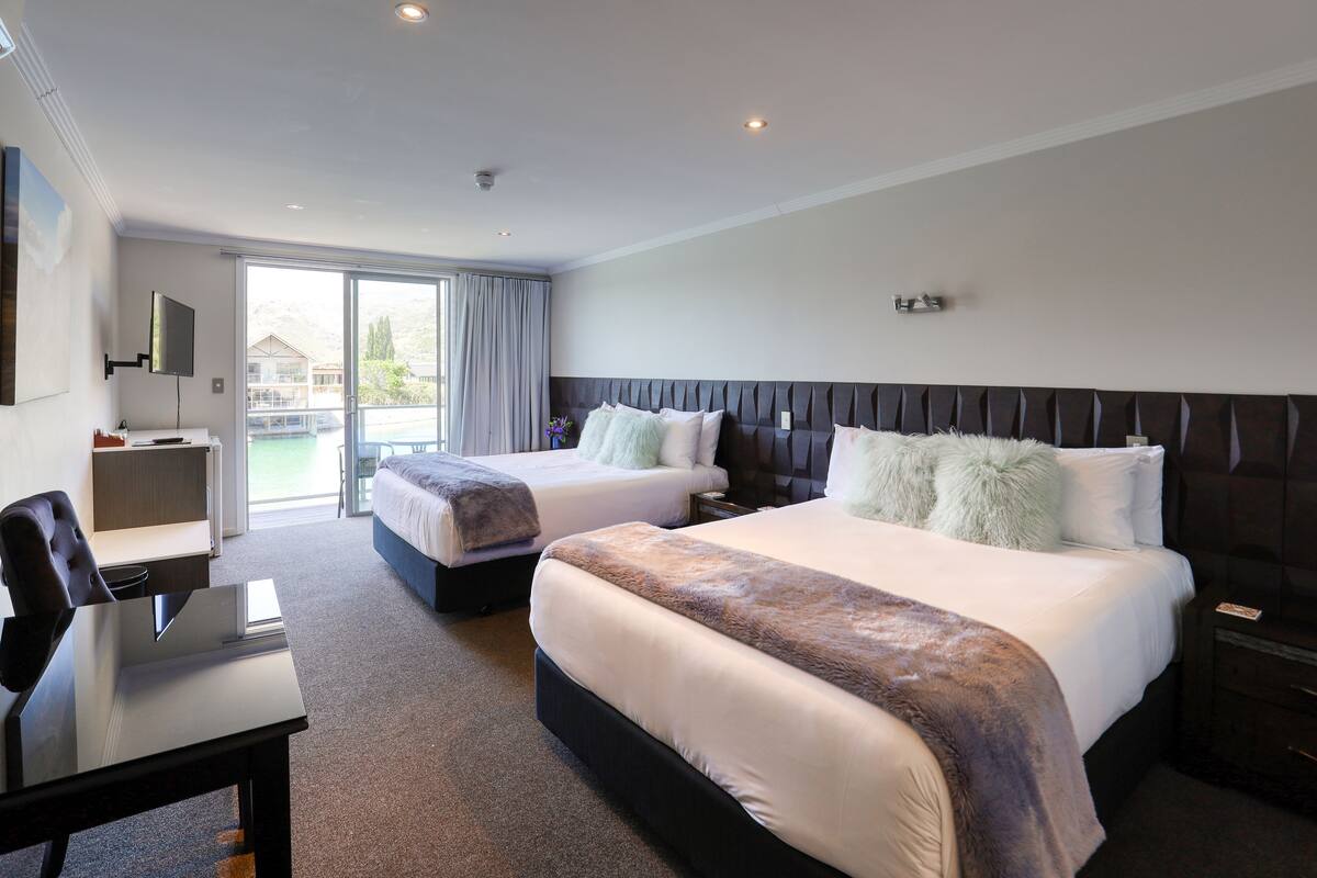 A hotel room with two beds, a desk, and a chair.