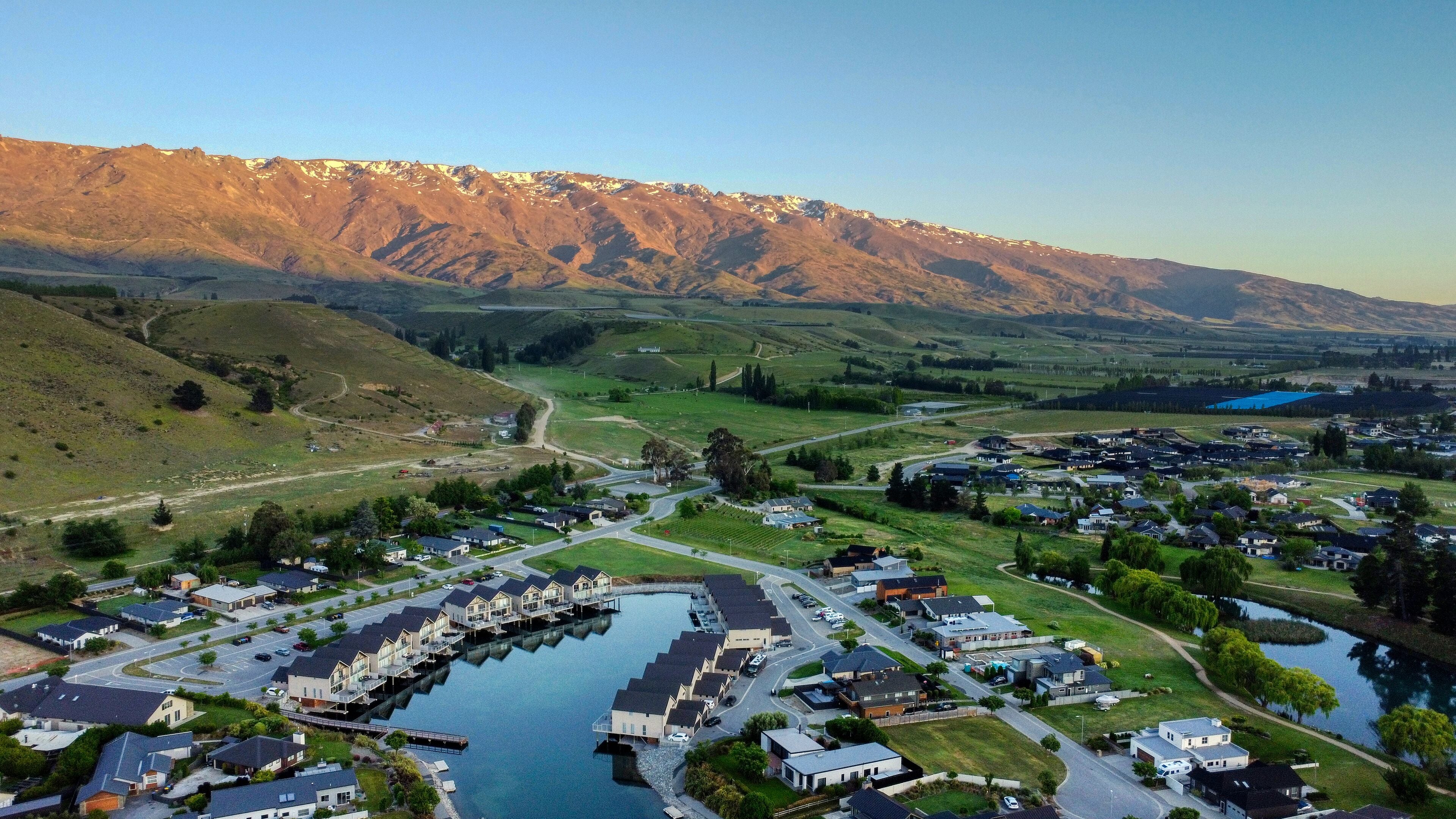 A residential area with houses, a marina, and a mountain backdrop.