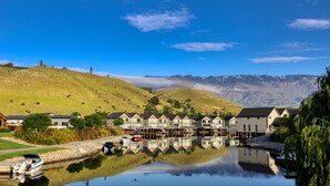 A waterfront property with a row of houses, a dock, and a calm lake reflecting the buildings. - Lake Resort by Marsden (Mount Pisa)