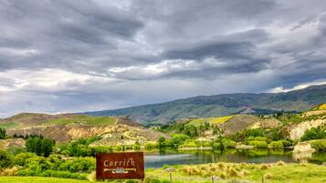 A sign reading "Carrick" in a rural landscape with a lake, hills, and a cloudy sky.