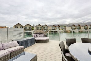 A deck with outdoor seating, overlooking a marina with boats and a row of houses. - Lake Resort by Marsden (Mount Pisa)
