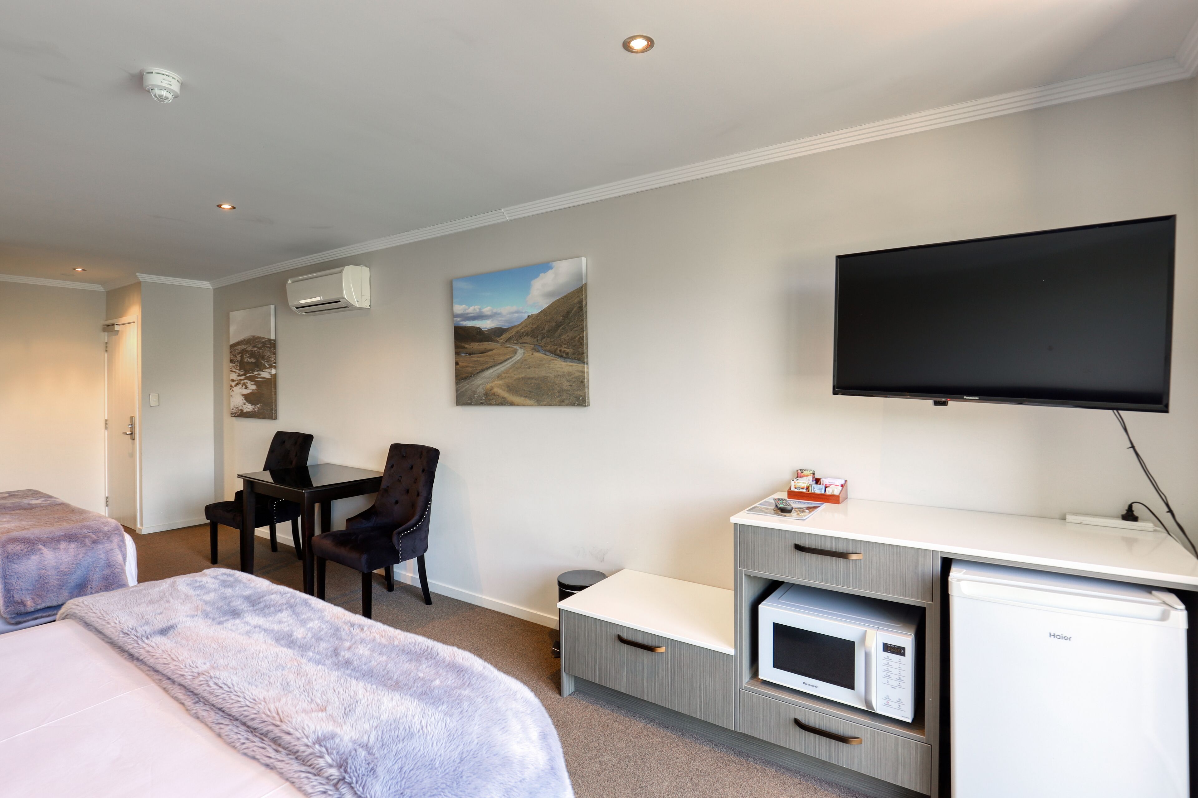 Habitación de hotel con dos camas, un escritorio con silla, televisor de pantalla plana, microondas y equipo de aire acondicionado.