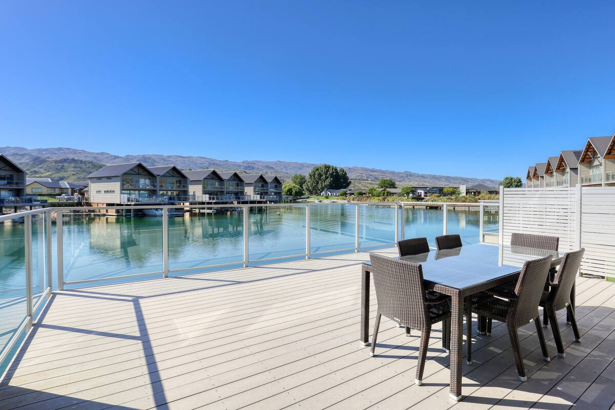 A poolside area with a table and chairs, overlooking a pool and mountains.