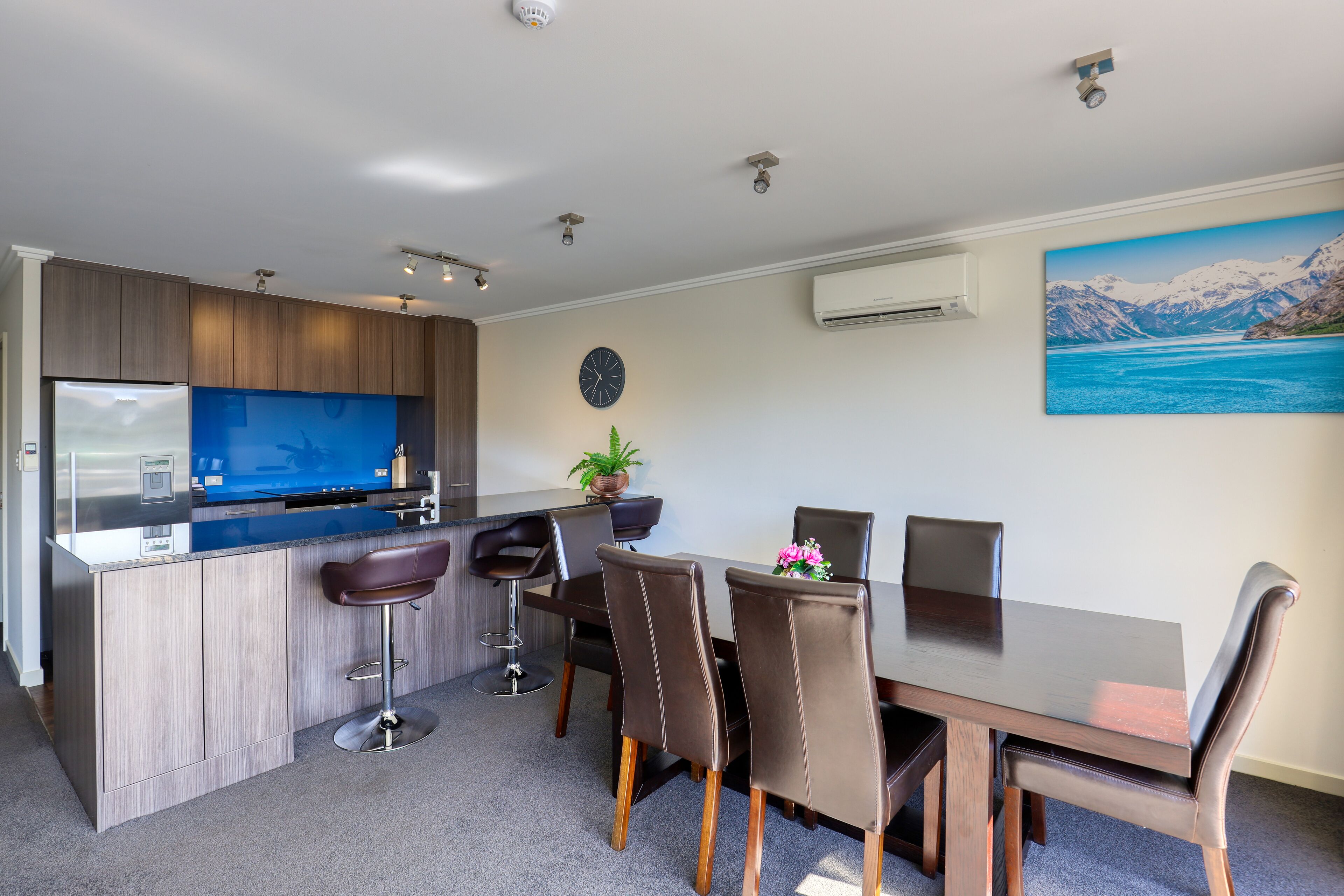 A modern kitchen with a built-in island, bar stools, and a dining area with a table and chairs.