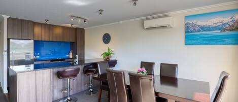 A modern kitchen with a built-in island, bar stools, and a dining area with a table and chairs.