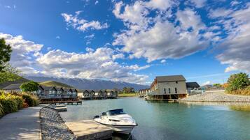 A waterfront property with a dock, a boat, and a row of houses with a mountain backdrop.