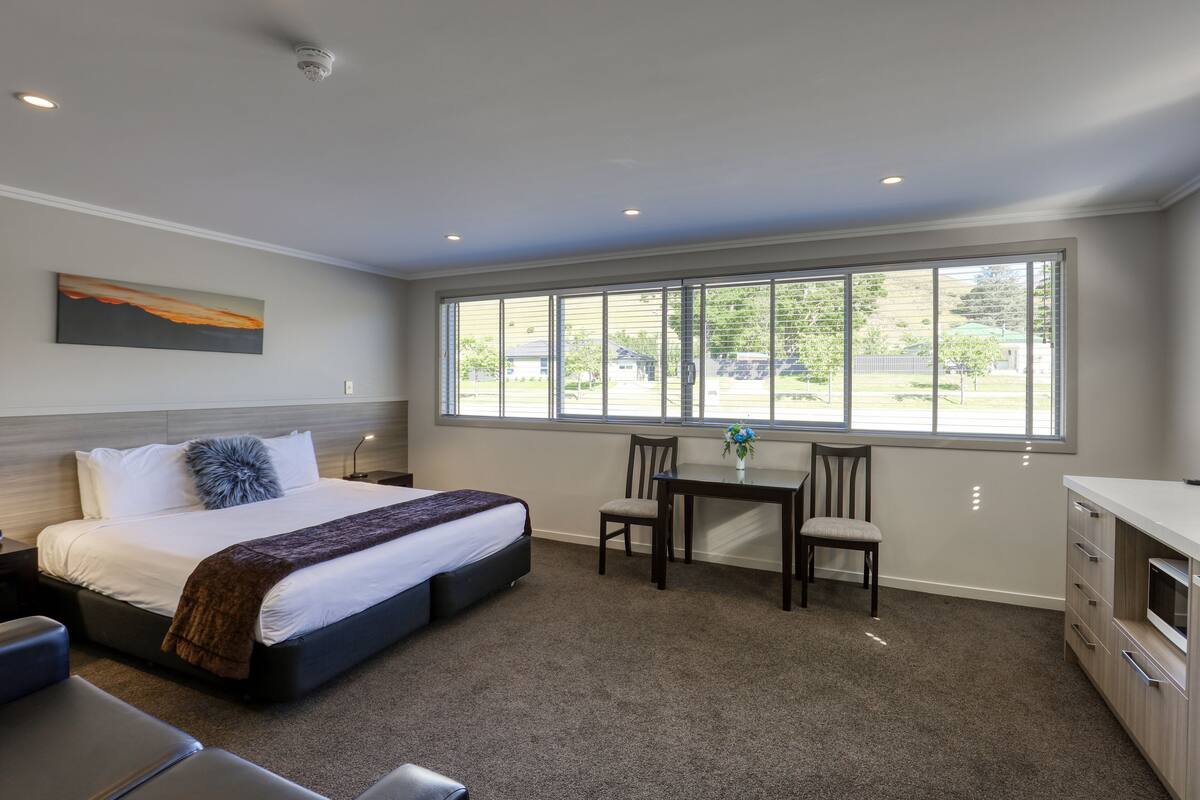 A bedroom with a bed, a desk, and a chair.