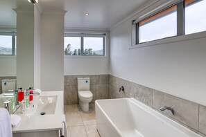 A modern bathroom with a bathtub, toilet, and sink. - Lake Resort by Marsden (Mount Pisa)