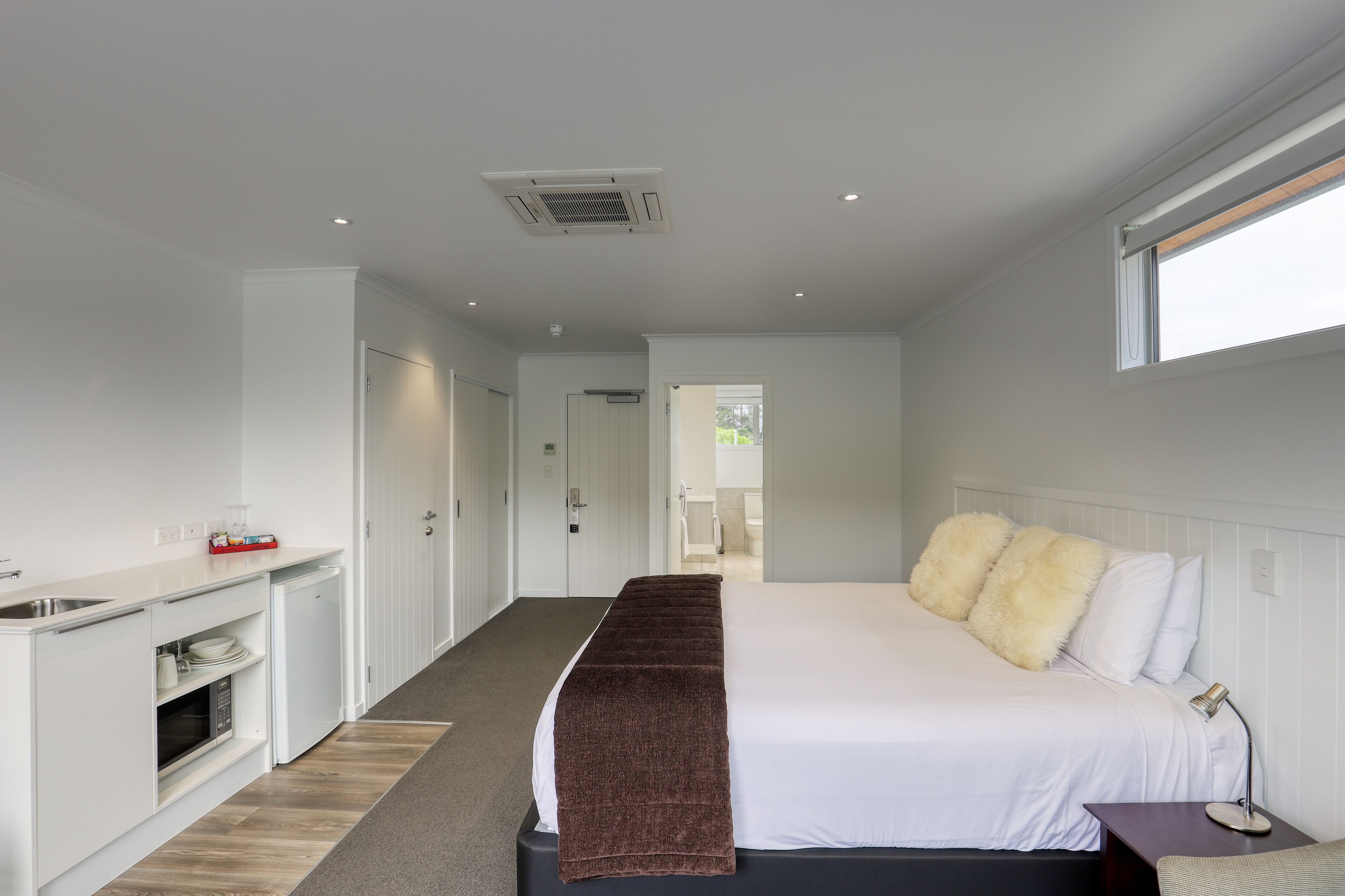 A bedroom with a bed, bedside table, and a view of the bathroom.