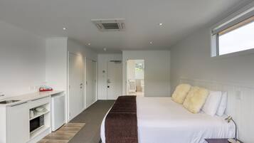 A bedroom with a bed, bedside table, and a view of the bathroom.