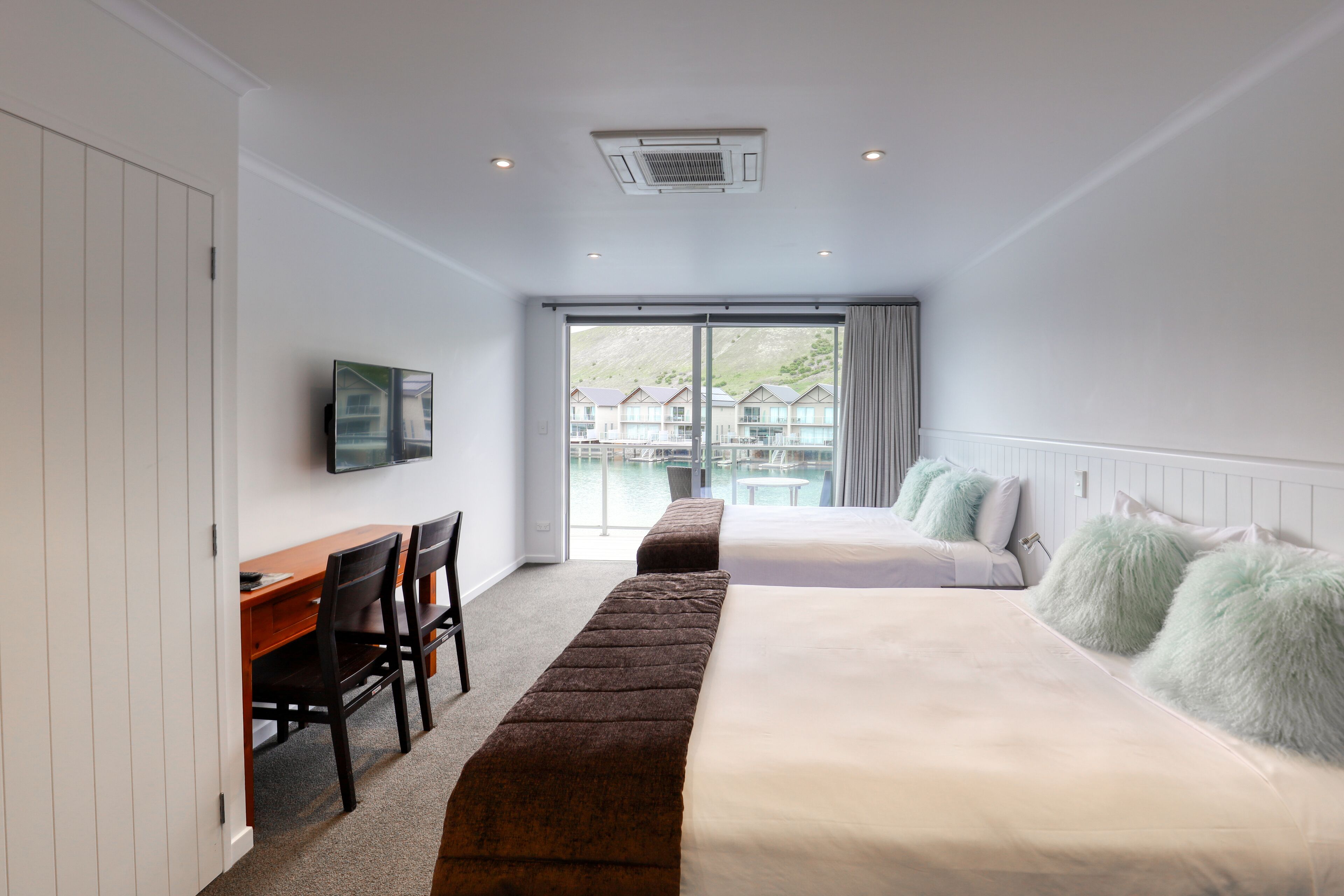 A modern hotel room with a large bed, a desk, and a TV.