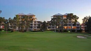 Ein Golfplatz mit Clubhaus und Wohnhäusern im Hintergrund.