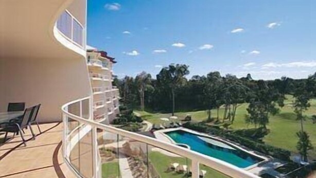 Ein Balkon mit Blick auf ein Schwimmbad und einen Golfplatz.