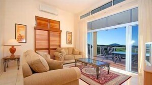 Ein geräumiges Wohnzimmer mit einem großen Glasfenster, das auf einen Balkon im Freien führt.