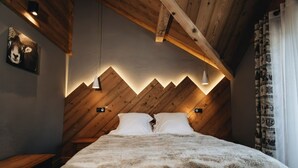 Un dormitorio acogedor con techo de madera, una cama con manta suave y una lámpara de pared.