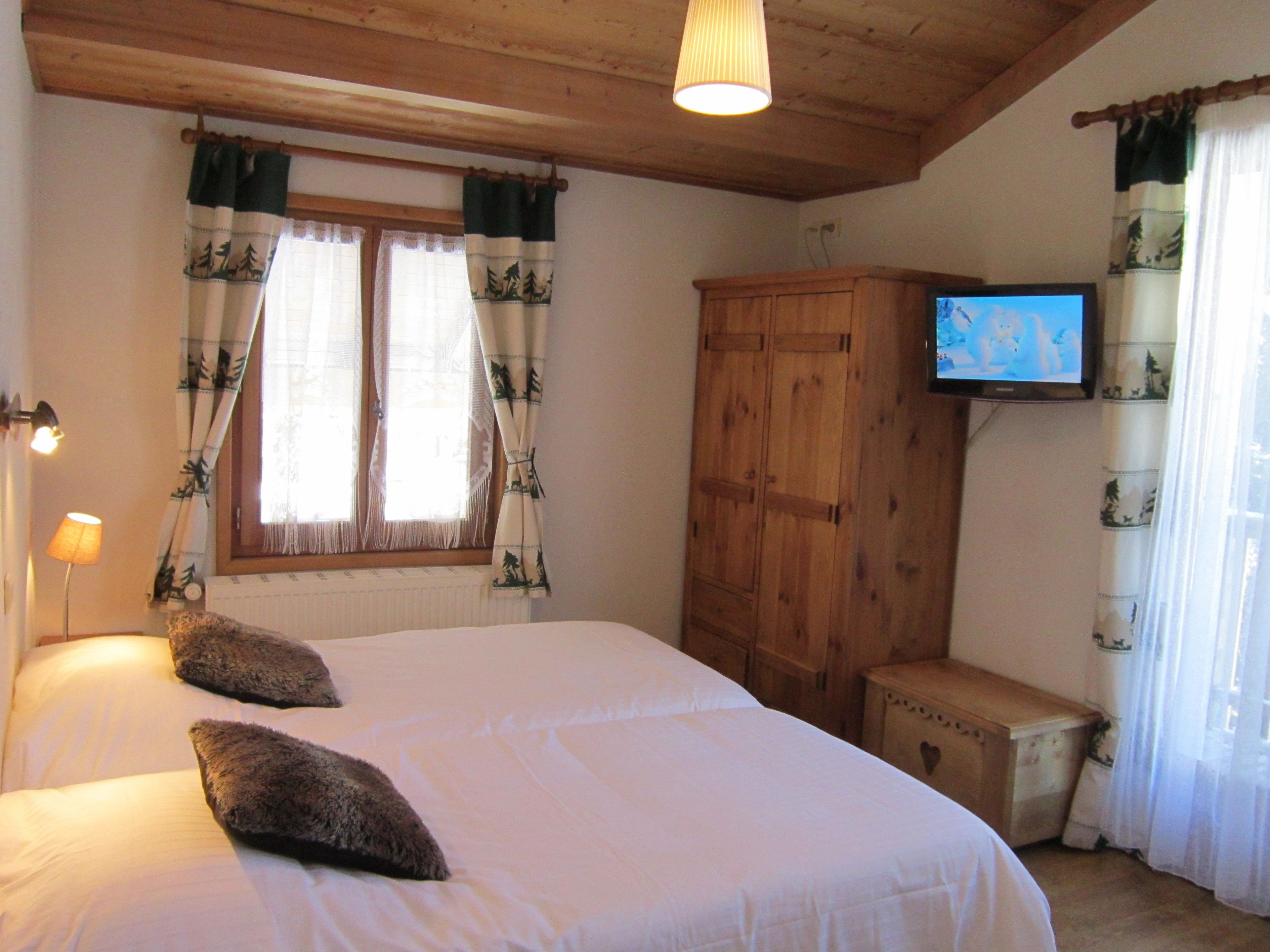 Ein Schlafzimmer mit einem großen Bett, einem Holzschrank und einem Fernseher an der Wand.