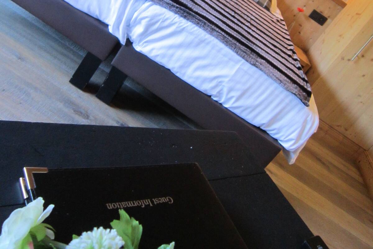 A hotel room with a large bed, two bedside lamps, and a wooden floor.