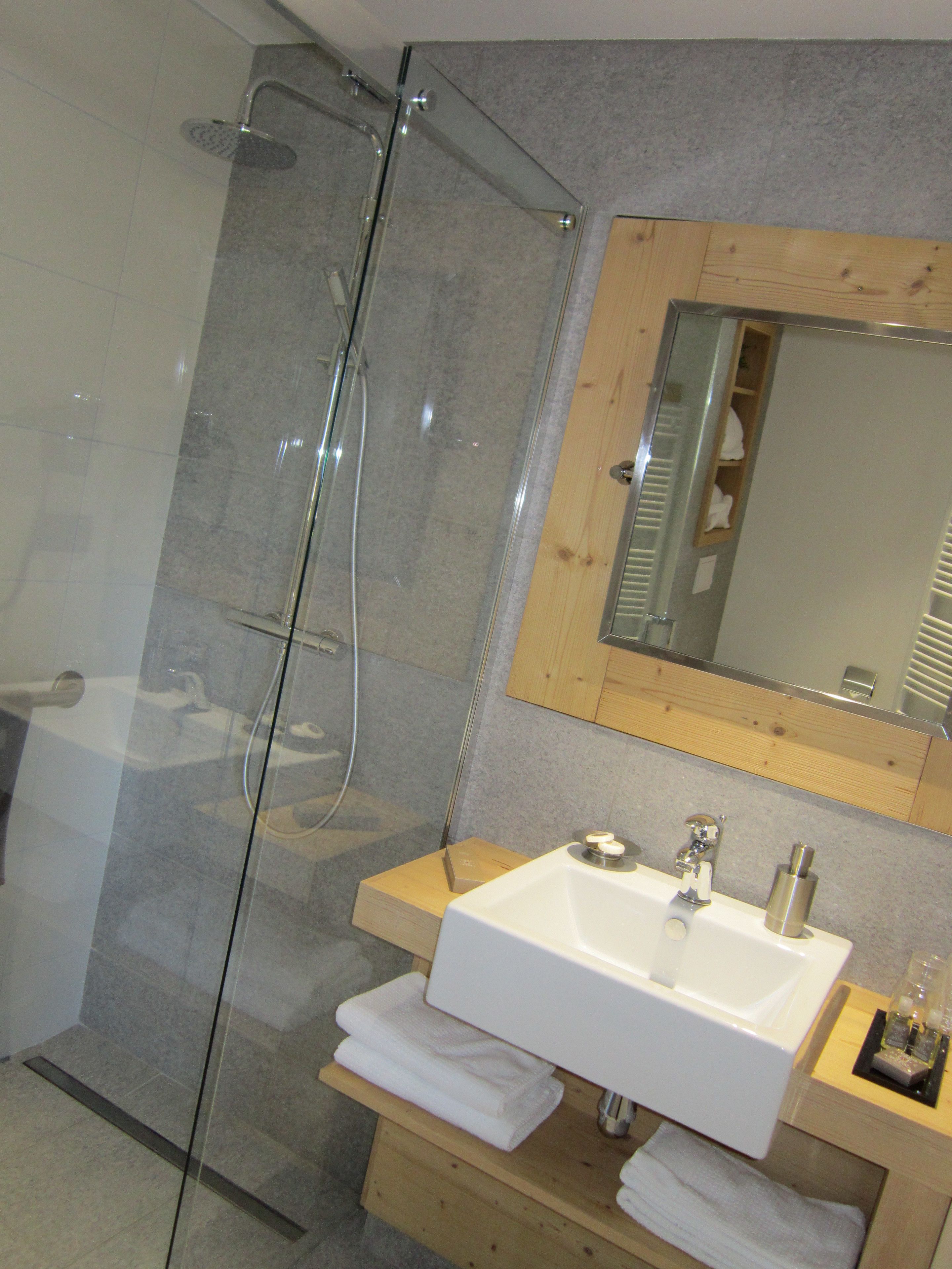 A modern bathroom with a glass-enclosed shower, a white sink, and wooden cabinetry.