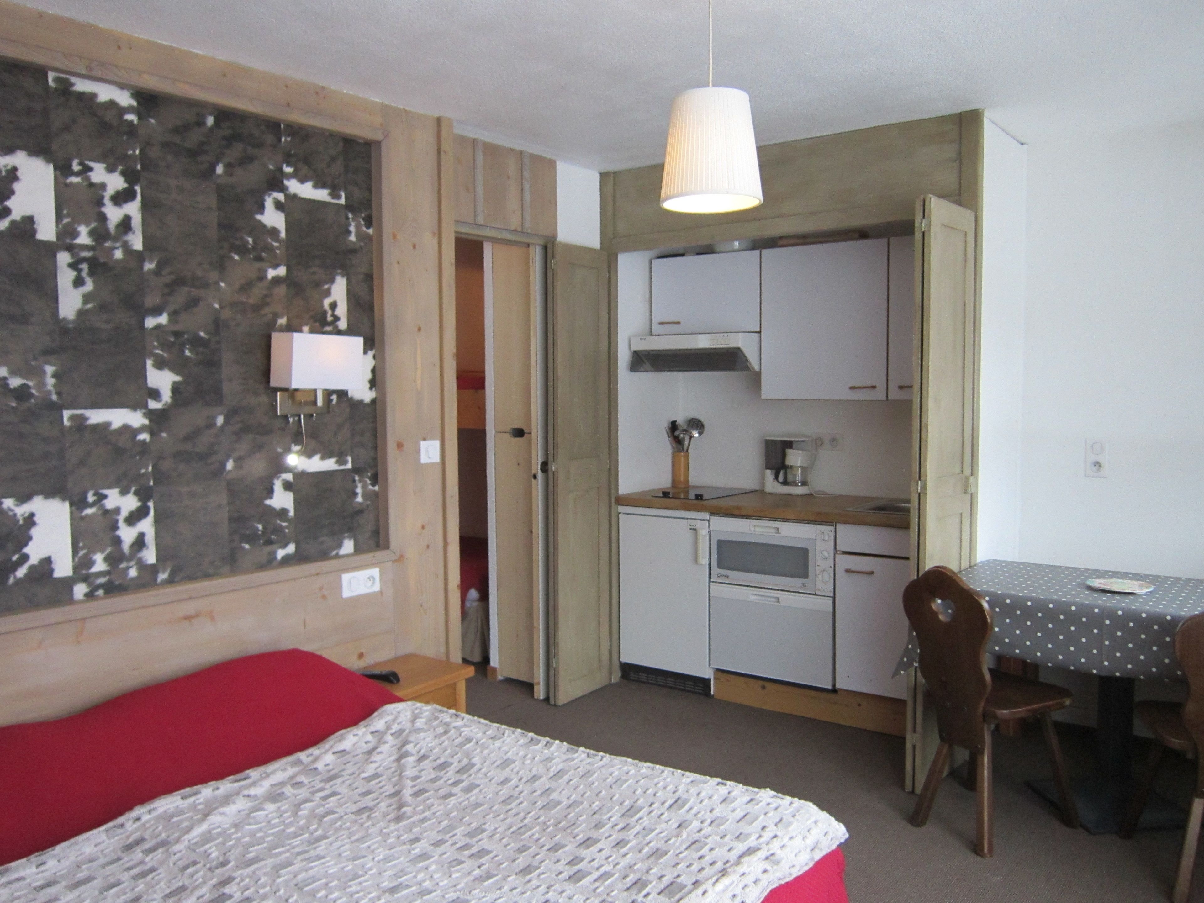 A compact room with a bed, a kitchenette, and a dining area.
