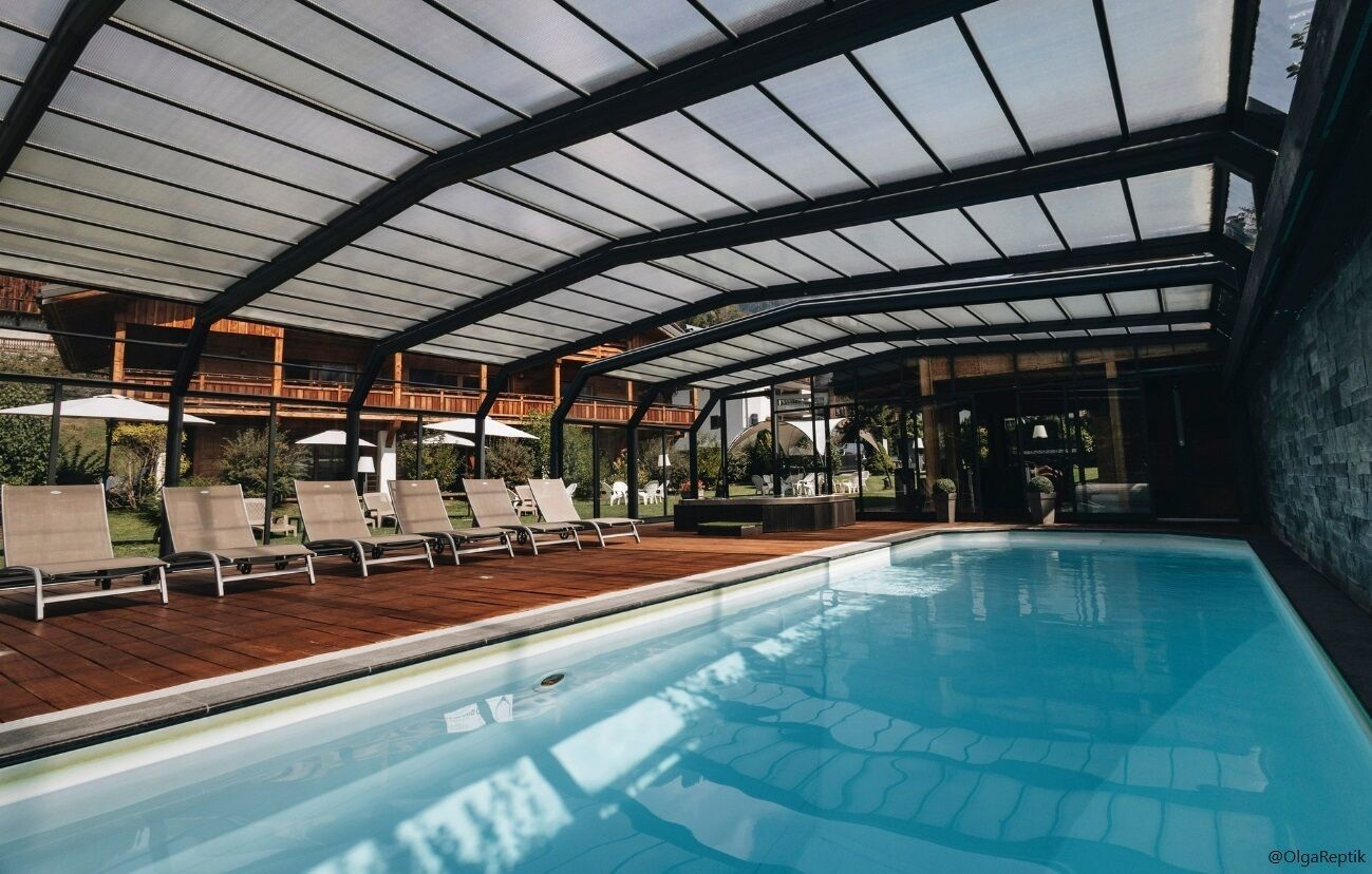 A swimming pool with lounge chairs and a covered area.