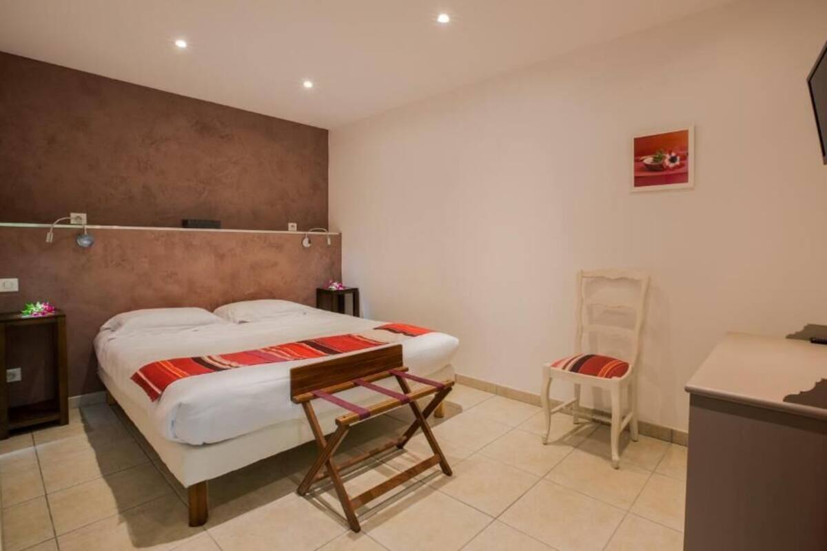 A bedroom with a bed, bedside tables, a chair, a TV, and a picture on the wall.
